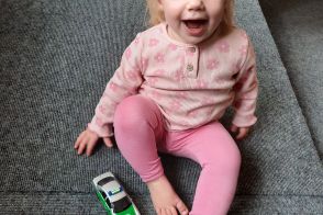 junges Mädchen läst ein Auto das Spielpodest runterfahren